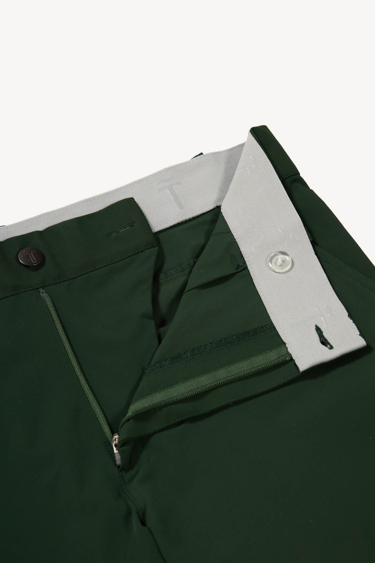 Close-up of green pants with a grey waistband on a white background