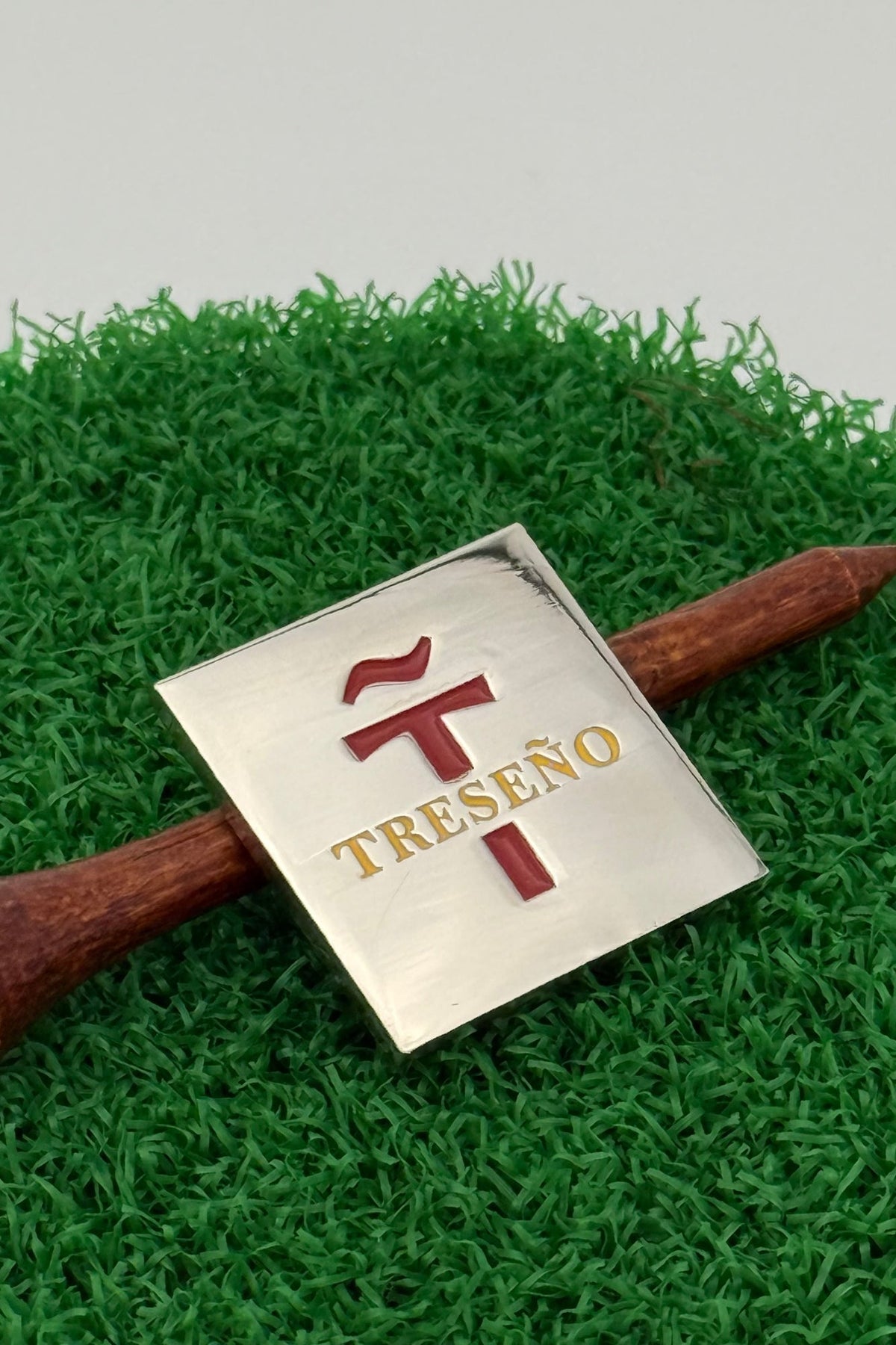 silver golf ball mark with Treseño embossed in red and yellow