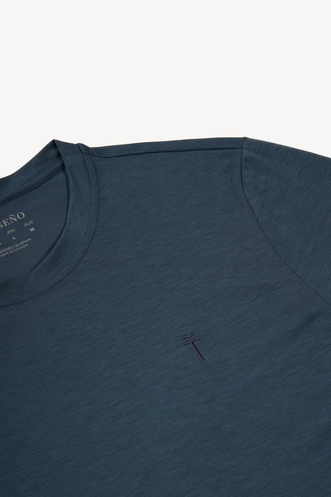 Blue grey t-shirt with a small logo on a white background