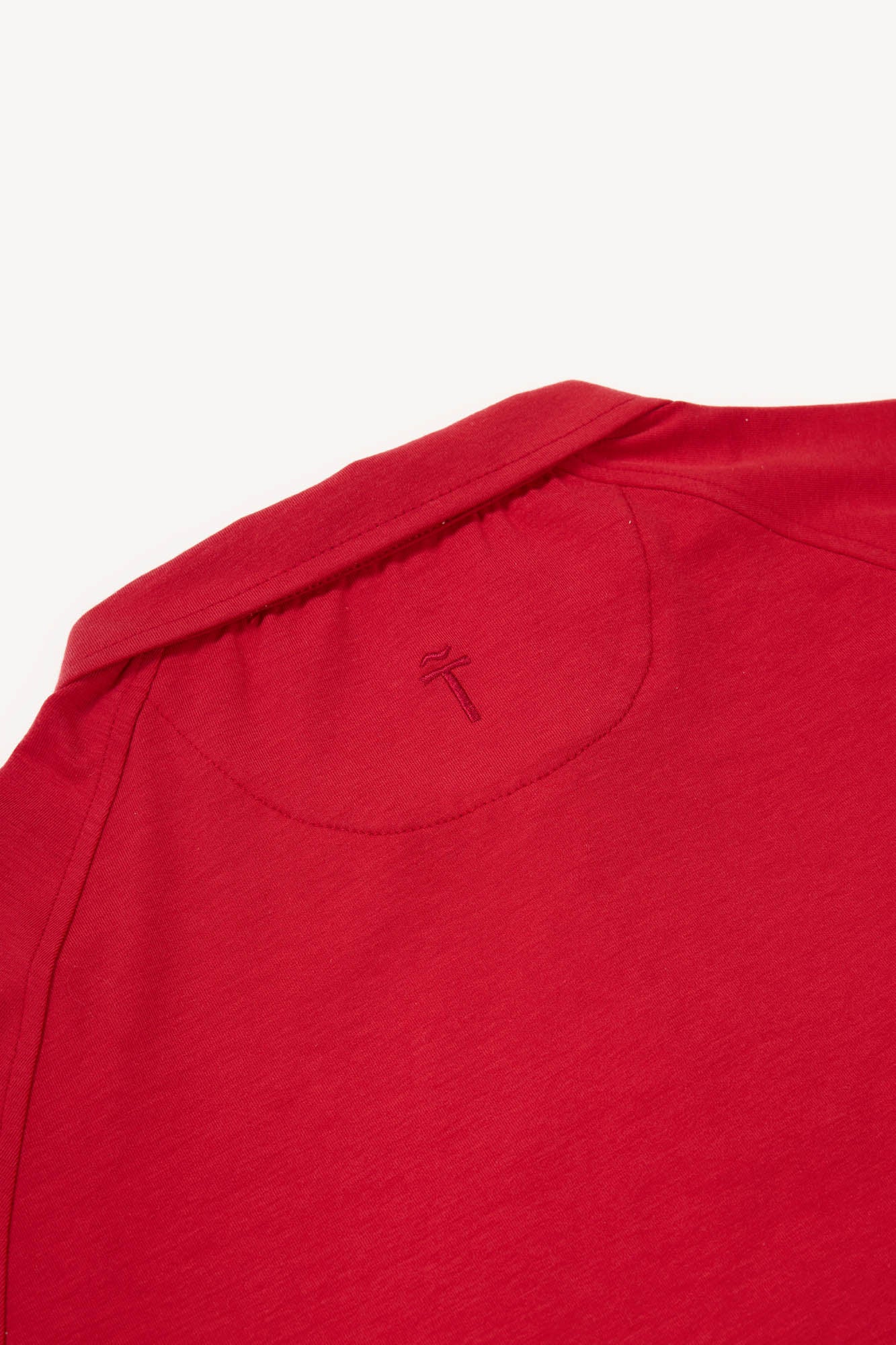 Close-up of a red polo shirt with a brand logo on a white background