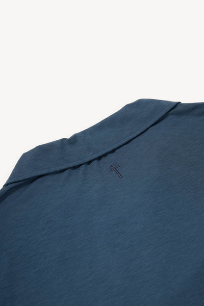 Close-up of a blue grey cashmere polo  with a subtle brand logo on a white background