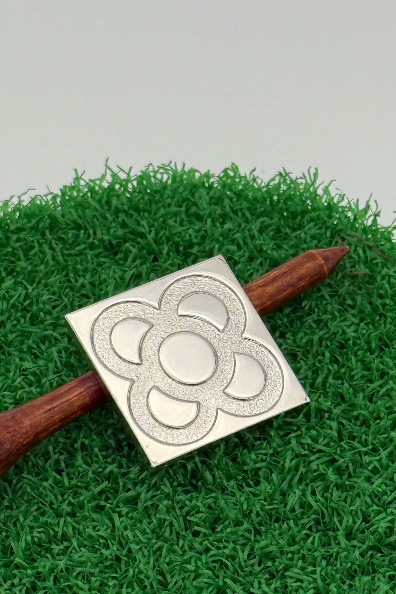 silver golf ball mark with Barcelona panot engraving