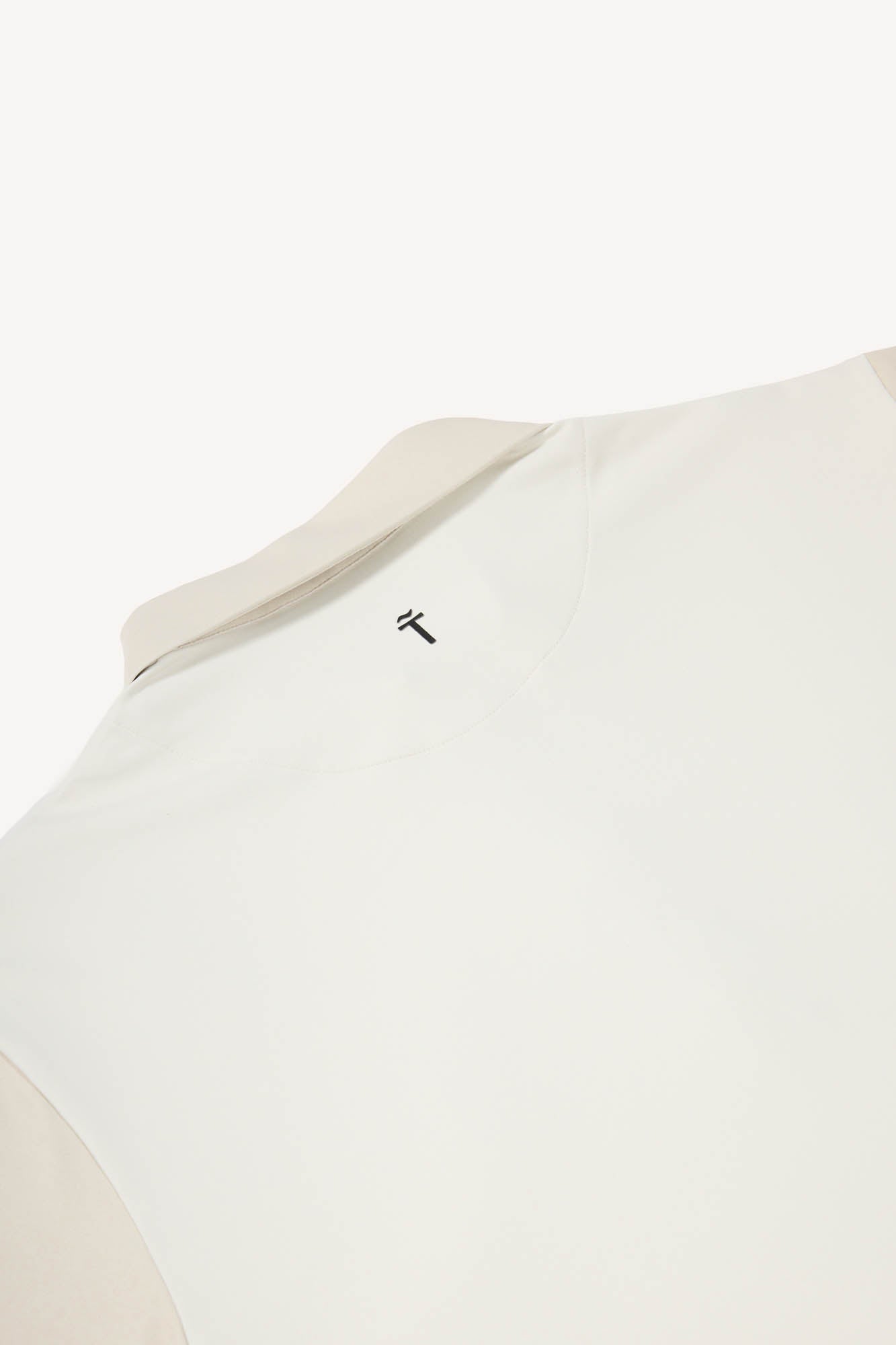 Close-up of a beige garment with a brand logo on a white background