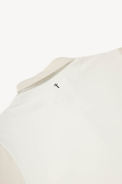 Close-up of a beige garment with a brand logo on a white background