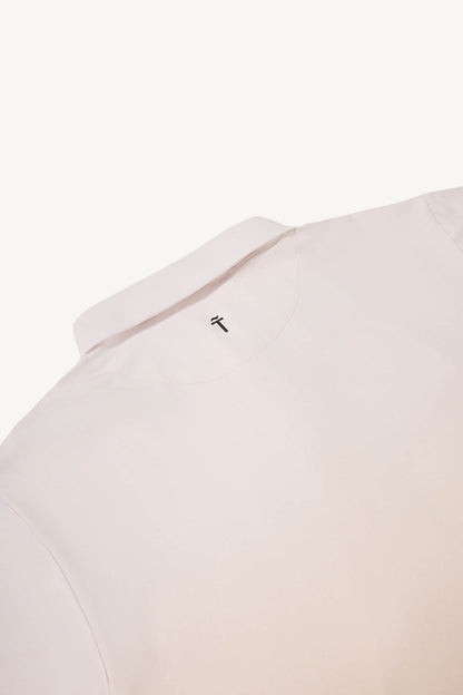 Close-up of a light tan polo shirt with a small logo on the collar against a white background