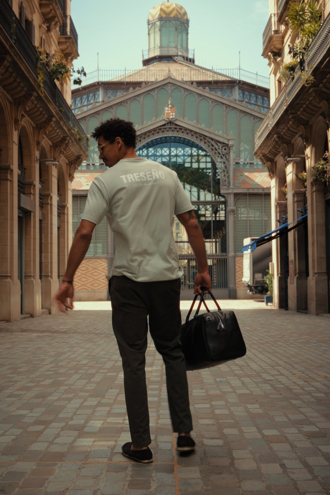 Man walking through an architectural street with a large building in the background