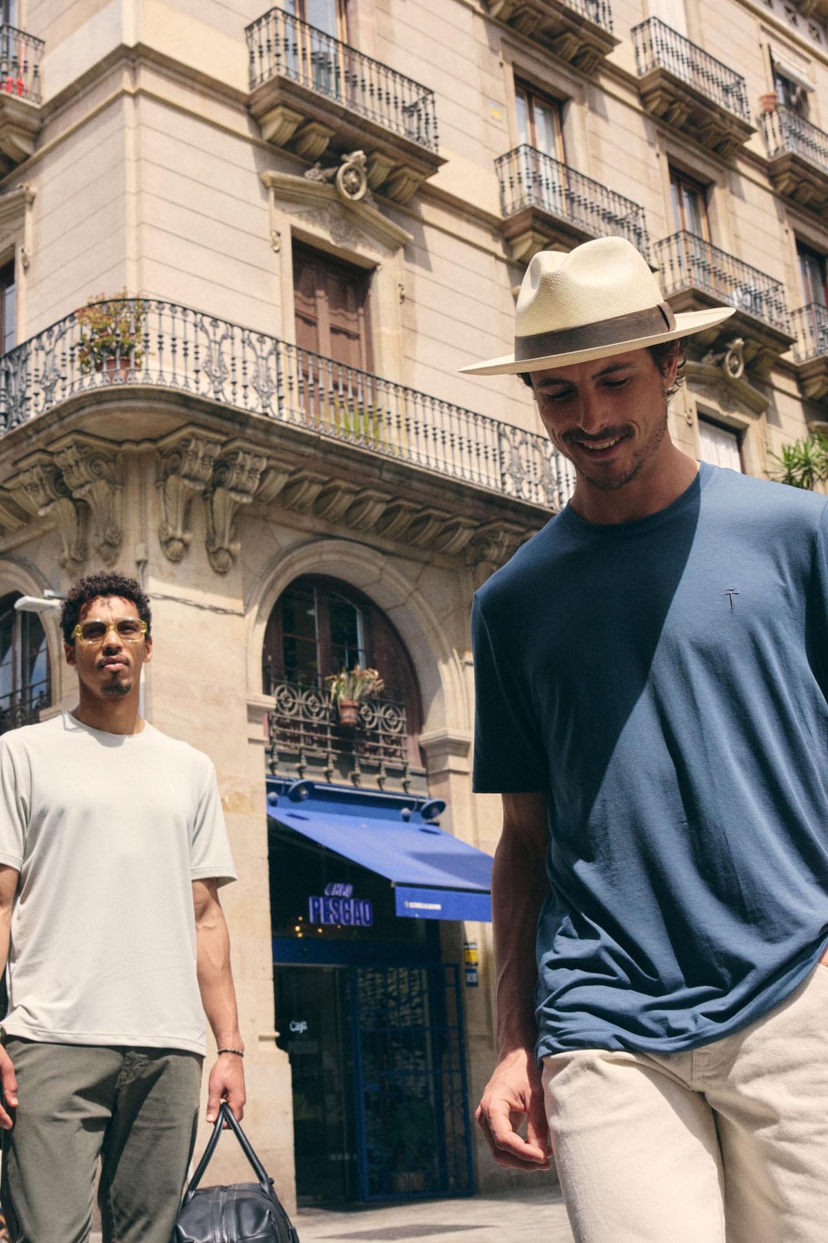 Two men walking on a street with a building in the background