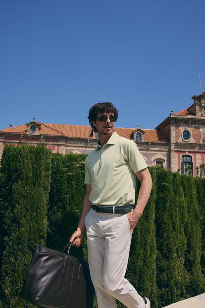 Man standing outdoors with a building and blue sky in the background