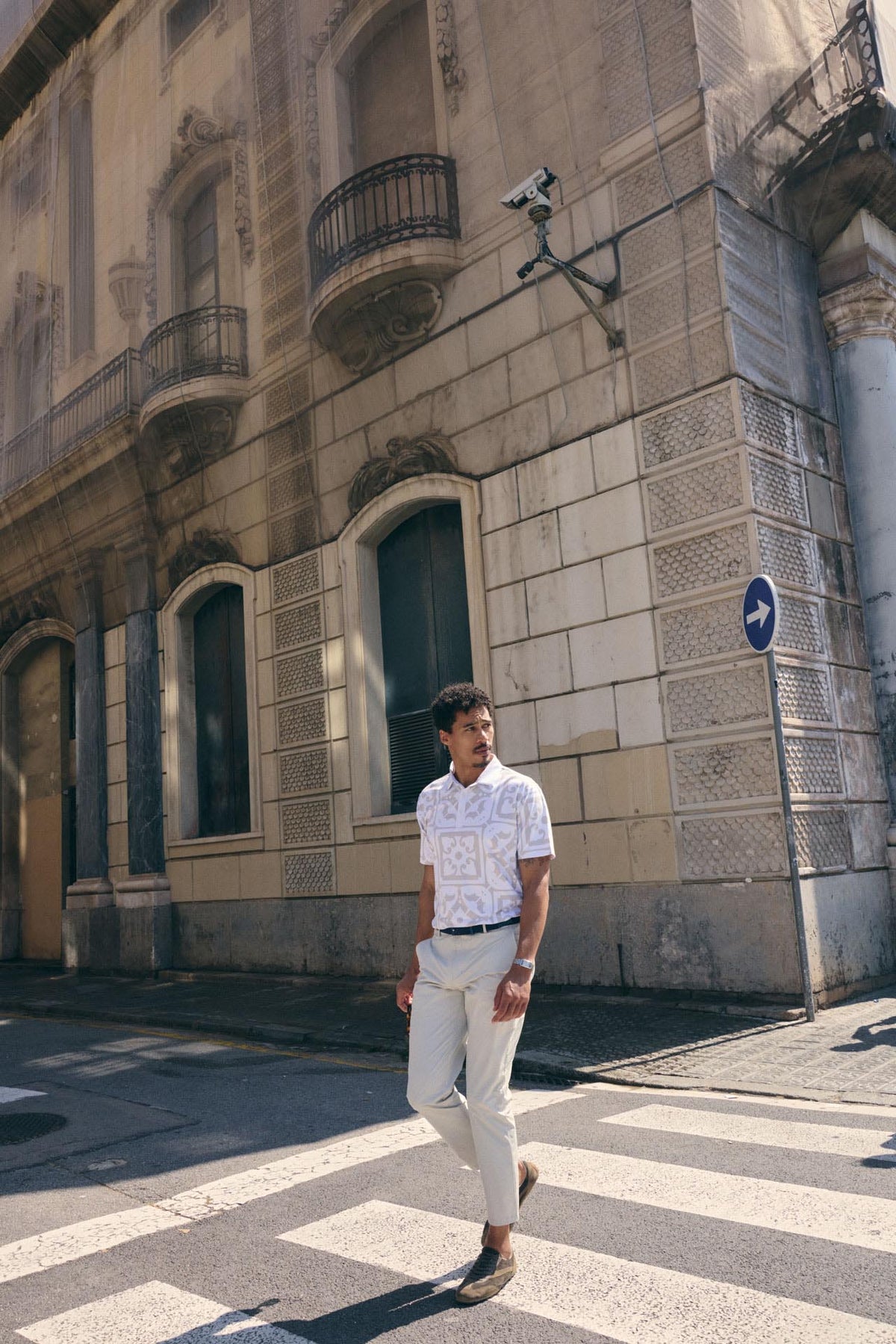 Man walking on a street in an urban setting with a building in the background