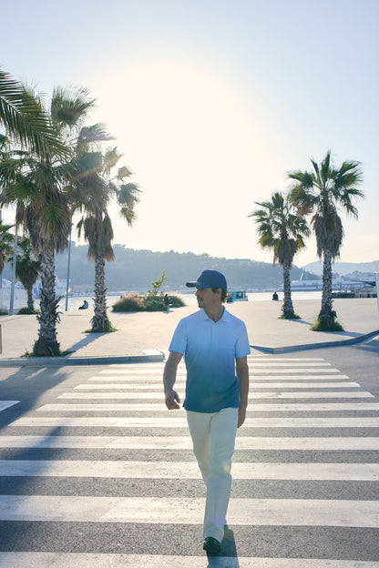 Man walking on a pedestrian crossing with palm trees and a clear sky in the background