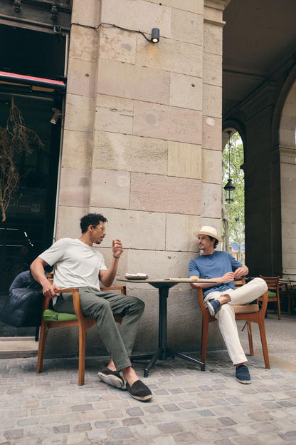 Two men sitting at a table outside a building, engaged in conversation.