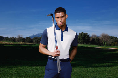 Man holding a golf club on a golf course with a clear blue sky