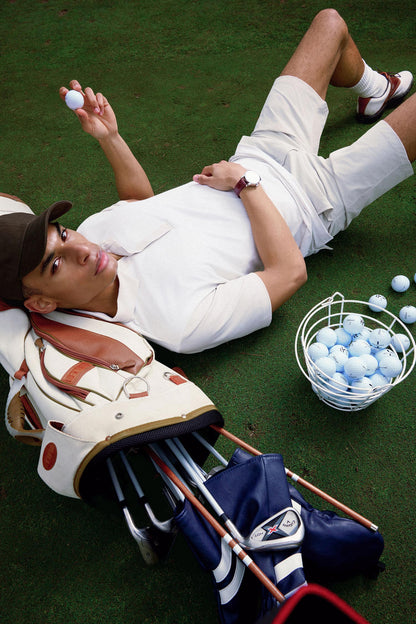 Person lying on grass with golf equipment and balls